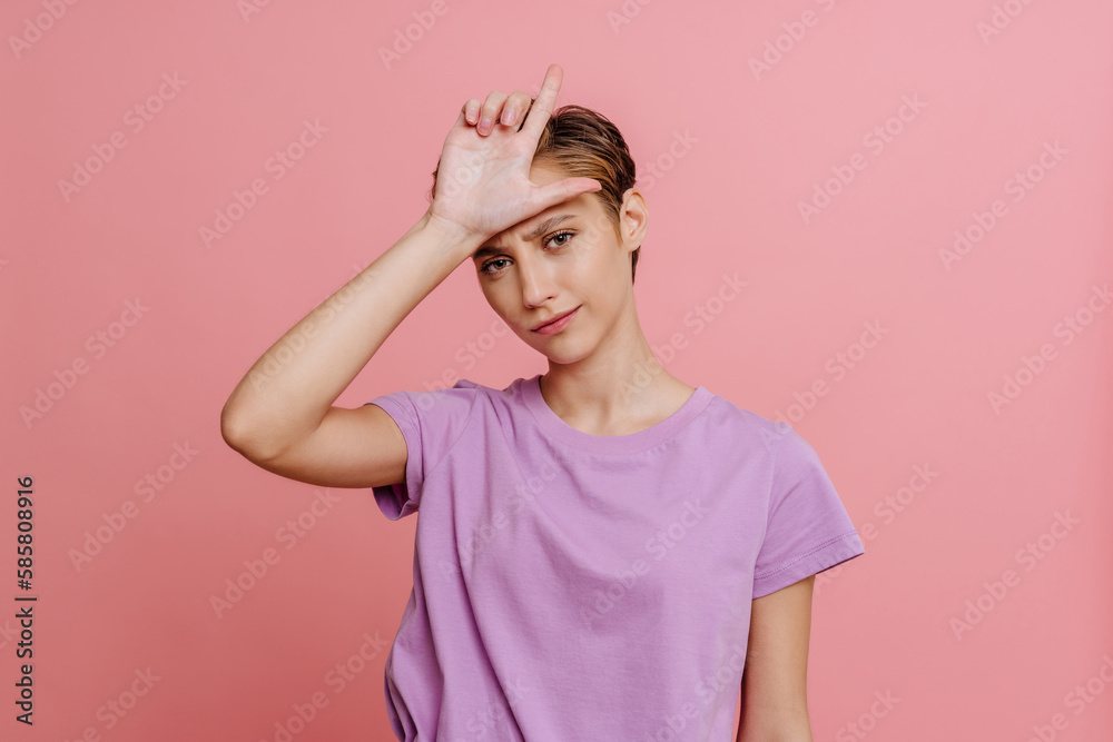 Portrait of young short-haired beautiful sad woman showing loser gesture Portrait of young short-haired beautiful sad woman showing loser gesture