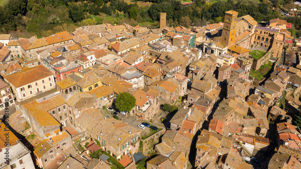 Aerial view of the historic center of Sutri, near Viterbo and Rome, Italy. The Romanesque cathedral with its bell tower dominates the city. All houses have traditional red tiled roofs in the old town.