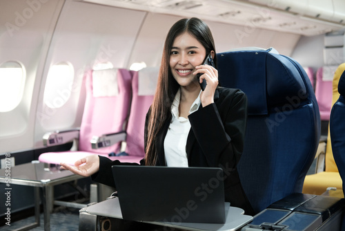 Young pretty businesswoman flies to a business meeting on a charter plane calls her subordinates and checks their work