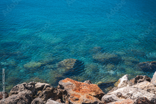 Stone seashore with clear transparent turquoise water and ripples on the surface of the water. Shot from above