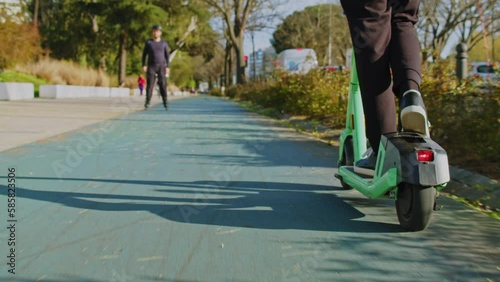Wallpaper Mural Low angle view to human legs rides on electric scooter  in  the city.  Man in a modern shoes moving on an electric scooter in the street. Ecological transport.  Soft focus. Slow motion. Back view Torontodigital.ca