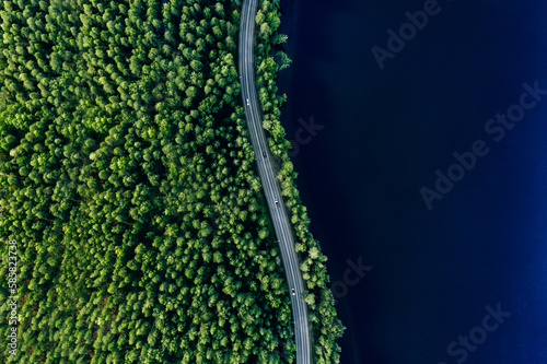 Fototapete Aerial view of road in green woods and blue lakes water in Finland