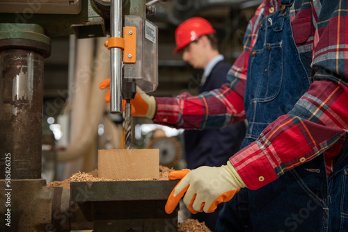 Craftman working on a wood solid inside of a factory with his boss beside him