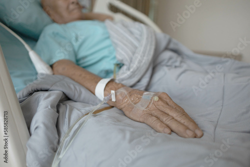 old patient hand with safety needle on back palm, senior man has health issue and get healing operation from government hospital treatment by expertise doctor, an illness man hand lay on white sheet. 