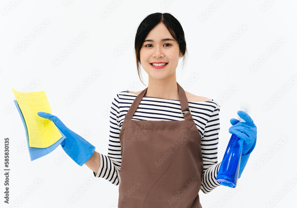 Housekeeper woman holding blue bottle with cleaner liquid and sponge in hands, female wearing white t shirt ,brow apron and blue gloves, looking smiling directly at camera, posing against white wall. Housekeeper woman holding blue bottle with cleaner liquid and sponge in hands, female wearing white t shirt ,brow apron and blue gloves, looking smiling directly at camera, posing against white wall.