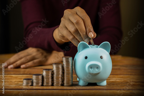 Woman using coin to put piggy bank by hand Concept of saving, accumulating, investing in the future, close-up