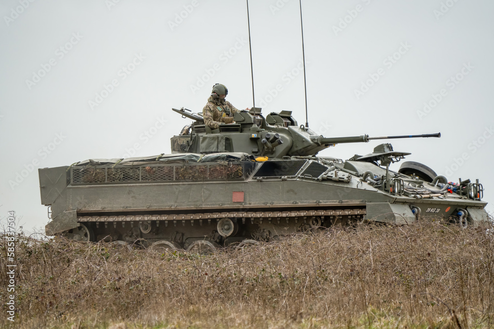 Naklejka premium British army Warrior FV510 with commander in action, moving across countryside