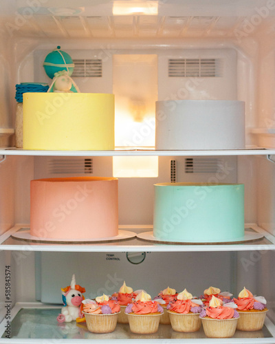 Pastry chef fridge with set of assorted colorful cakes before decoration