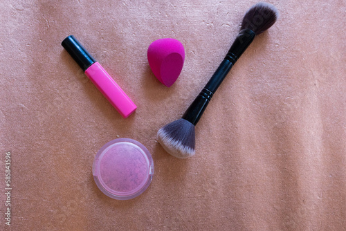 beauty concept, makeup brush and pink sponge blender with pink mascara tube on rose gold shimmery surface photo