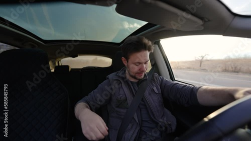 Man driving car and looking at phone at sunny day interior view
