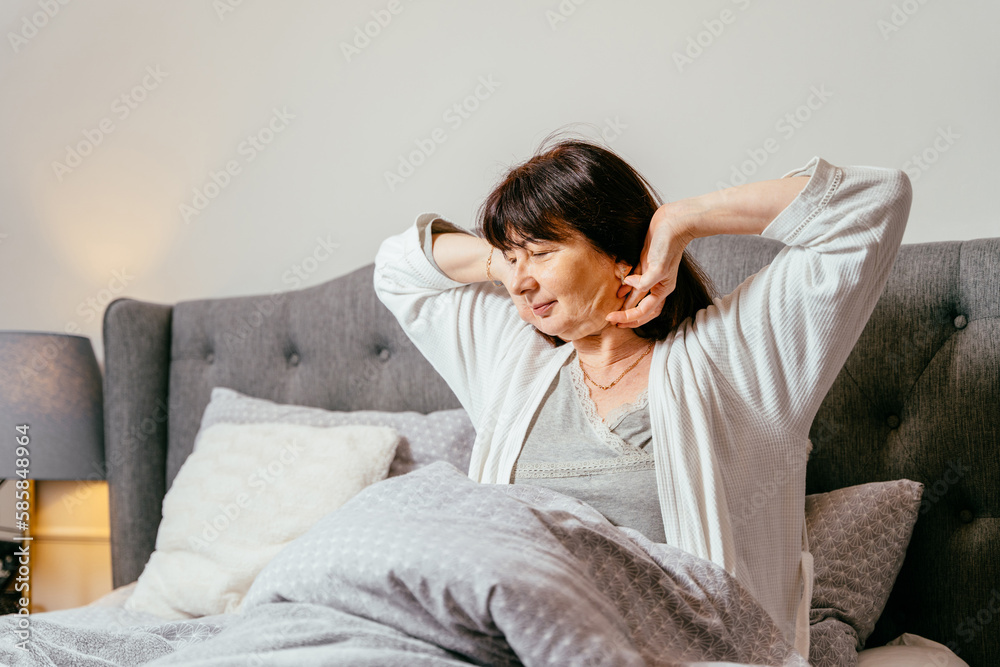 Feel hope and relax , alone at home. Smiling old middle age mature lady awake after healthy sleep sitting in cozy comfortable bedroom interior enjoy good morning. Feel hope and relax , alone at home. Smiling old middle age mature lady awake after healthy sleep sitting in cozy comfortable bedroom interior enjoy good morning.