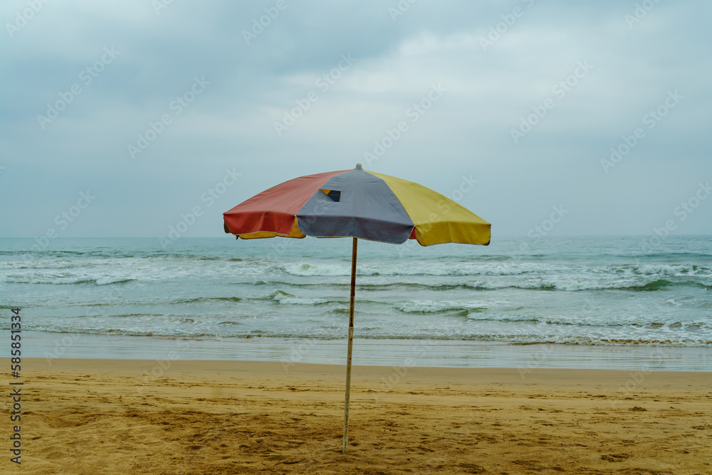 An old parasol stands on the beach