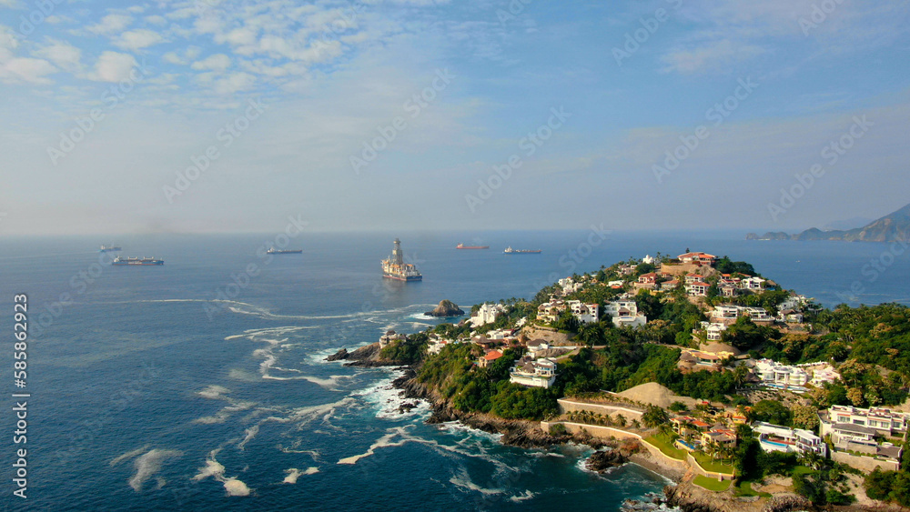 Aerial view of Peninsula de Santiago in city Manzanillo, Mexico. Beautiful bitch and luxury hotels and offshore   drilling ship platform and tanker ships  at anchor in the bay