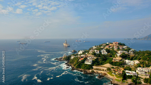 Fototapeta Naklejka Na Ścianę i Meble -  Aerial view of Peninsula de Santiago in city Manzanillo, Mexico. Beautiful bitch and luxury hotels and offshore   drilling ship platform and tanker ships  at anchor in the bay