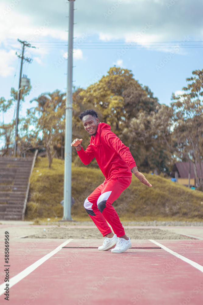 Obraz premium Joven afro bailando al estilo urbano en un parque, con hermosa vegetacion y cielo de fondo
