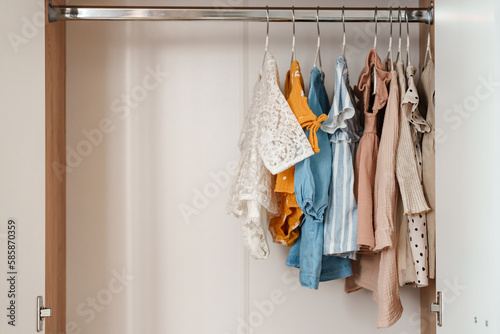 Children's clothes, girls' dresses hang on hangers in an open closet, dressing room