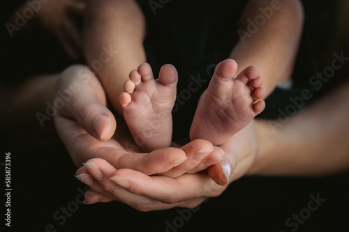 Color photo of baby's feet being held by loving parents. Close up.