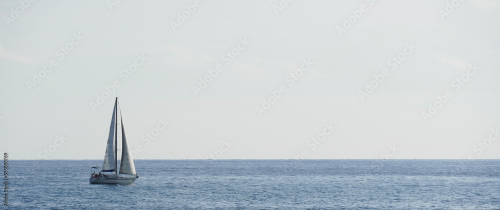 Boat sailing on summer vacation in the Mediterranean Sea. Sailboat in the water with space for text. White sailing boat. Sailing boat racing with white sails in open sea.
