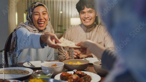 Eid Mubarak Muslim Asia family have Iftar dinner sister share bread to sibling for break fasting. Traditional food during Ramadan month at home, The Islamic Halal Eat and Drink at modern Islam.