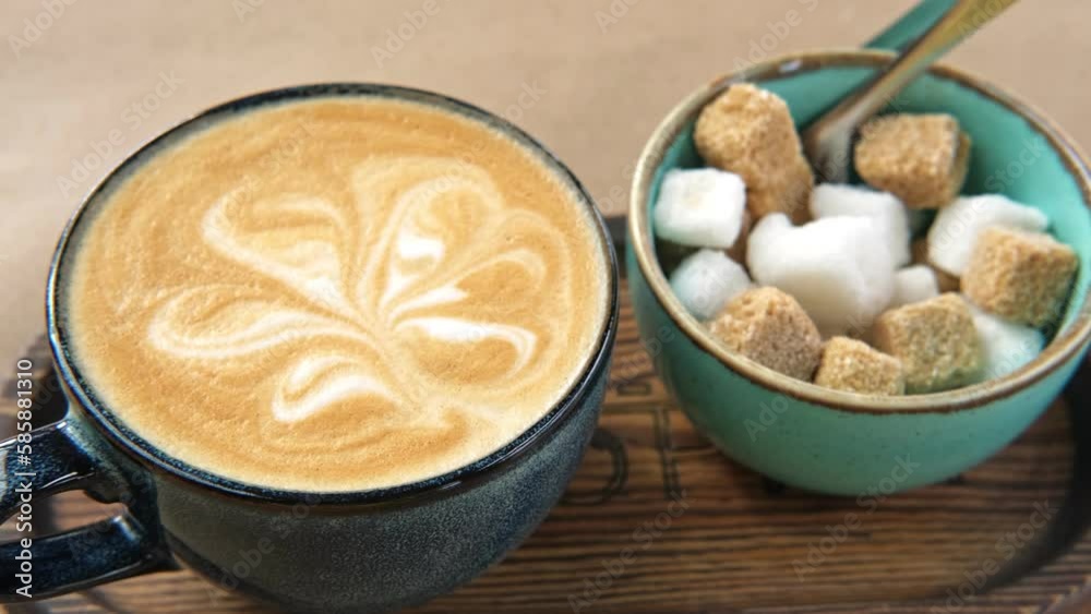 Blue Ceramic Cup of Hot Cappuccino with Flower Shaped Foam on Wooden Cafe Table. Beautiful Latte Art Froth. Trendy Authentic Modern Porcelain Set. Pottery Handmade Coffee Mug Served with a Sugar Bowl. Blue Ceramic Cup of Hot Cappuccino with Flower Shaped Foam on Wooden Cafe Table. Beautiful Latte Art Froth. Trendy Authentic Modern Porcelain Set. Pottery Handmade Coffee Mug Served with a Sugar Bowl.