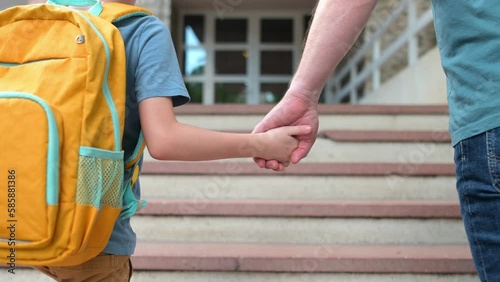 Little schoolboy with his father goes to school after summer holiday. Parent accompanies or meets the child. Quality education for children. Kids back to school concept.