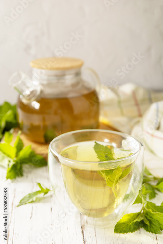 Cup and teapot of fresh natural herbal tea with fresh mint leaves on rustic wooden table. Organic aromatherapy relaxation medical healthy drink. Copy space.
