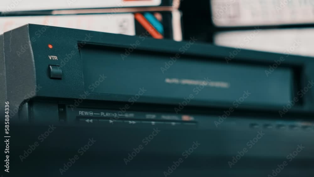 Eject VHS tape cassette from VCR player. Male hand pushes a button and