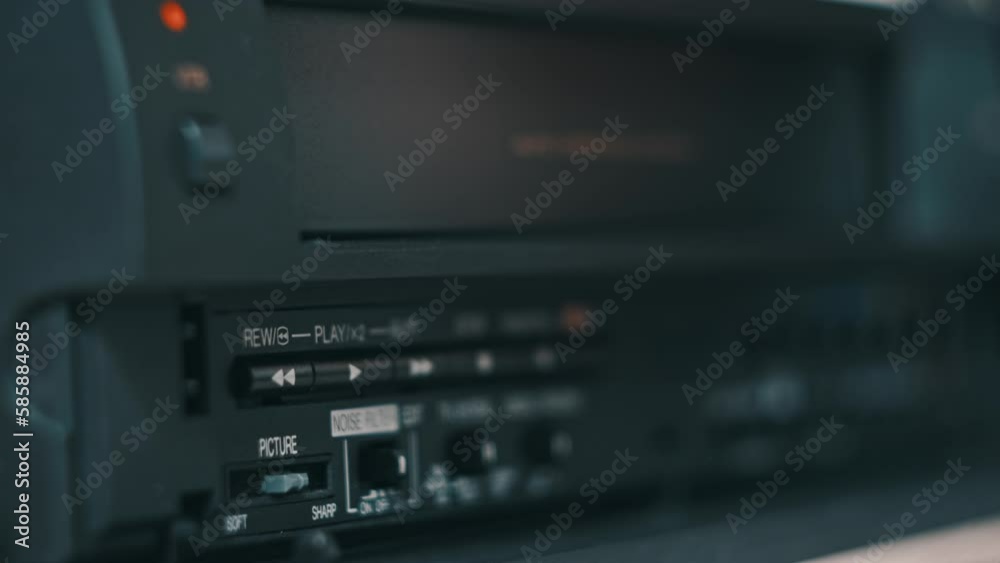 Eject VHS tape cassette from VCR player. Female hand pushes a button