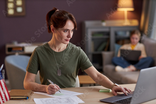 Portrait of young military woman using laptop and working at desk in office