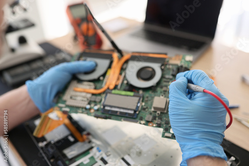 Repairman in gloves checkups computer motherboard in shop