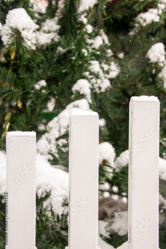 Snow on the white stakes of the fence