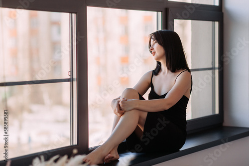 A girl with shoulder-length black hair is sitting by a huge window 4552.