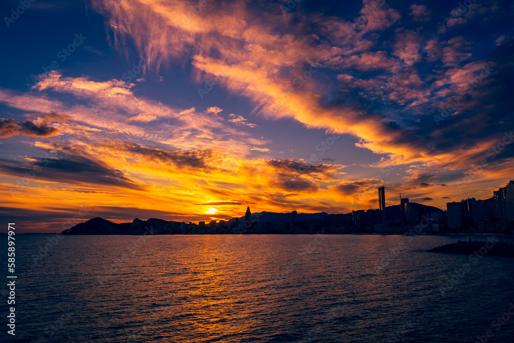 The skyscrapers behind Benidorms western beaches are silhouetted by the setting sun.