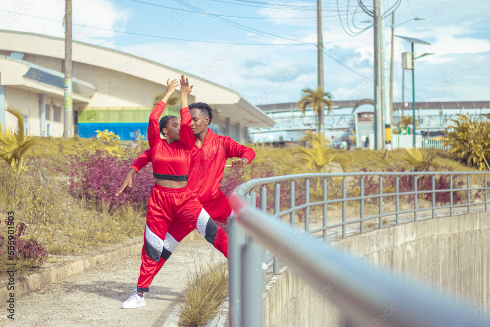 Fototapeta premium Pareja de bailarines afro realizan actuacion de baile en parque con hermosa vegetacion y hermoso cielo azul