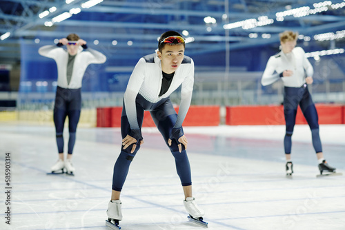 Young male athlete in sportive uniform ready to move forwards waiting for signal to start while standing on skating rink during training