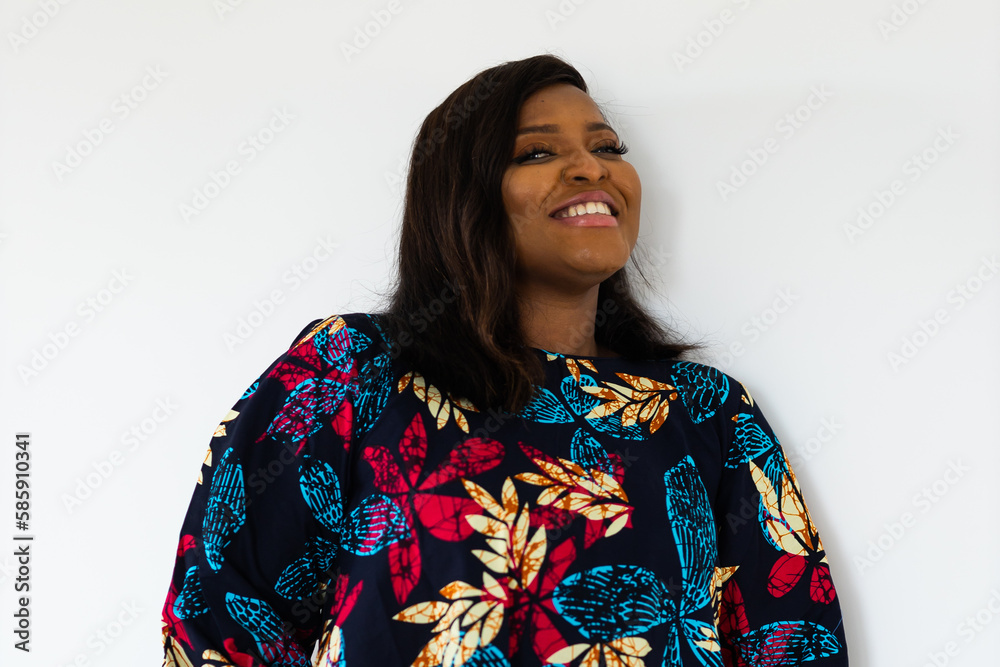 Smiling confident african american young woman wears stylish dress standing over white background in room - inclusion and diversity concept Smiling confident african american young woman wears stylish dress standing over white background in room - inclusion and diversity concept