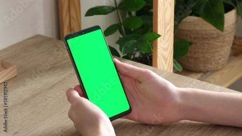 A man is holding a phone with a green screen. Online training. Communication online. phone in hand