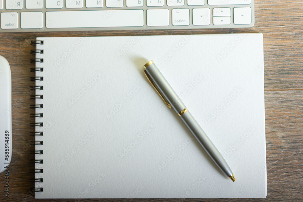 Notepad with pen and keyboard on wooden table Notepad with pen and keyboard on wooden table