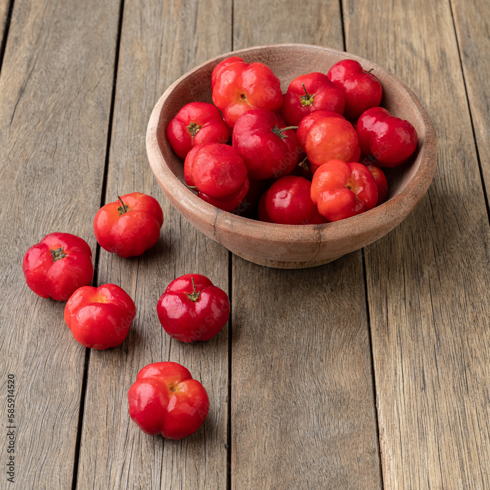 Acerolas or Barbados Cherries in a bowl over wooden table Acerolas or Barbados Cherries in a bowl over wooden table