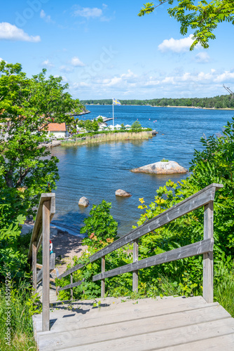 Sunny day in a small village bay on Vaxholm Island. Wooden staircase down to small beach. Stockholm Archipelago, Sweden photo