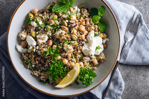 Bild auf Leinwand Healthy Salad made from Quinoa, Cucumber, Herbs, Pistachios, Chickpeas and Feta with lemon juice and olive oil