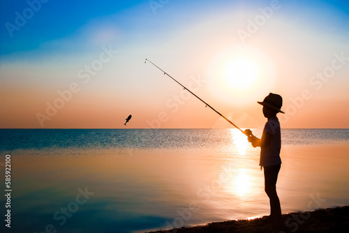 A Happy child fisherman fishing by the sea on nature silhouette travel