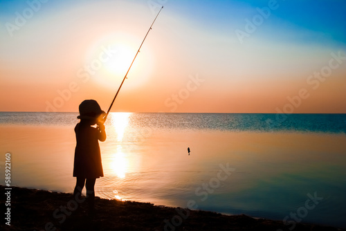 A Happy child fisherman fishing by the sea on nature silhouette travel © Kostia