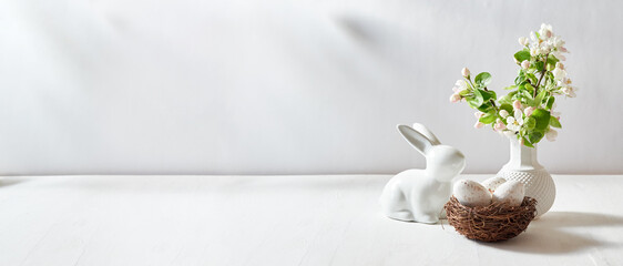Spring flowers in a vase and easter eggs on a white table. Easter background with copy space
