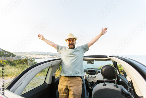 Happy man sitting in white convertible car with beautiful view and having fun - travel summer vacation and rental car concept