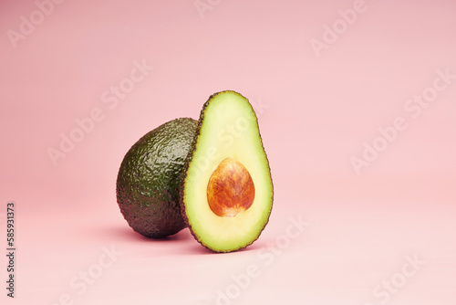 Fotografija Avocado slice with the pit isolated on the bright solid fond plain pink backgrou