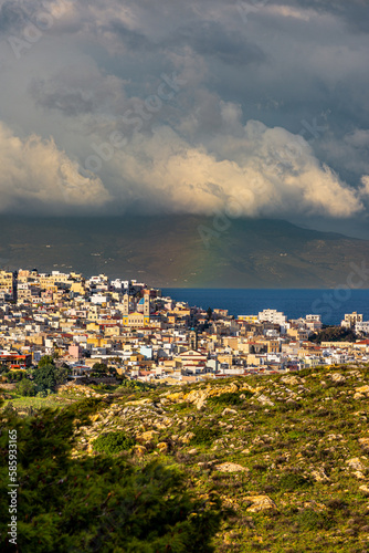 View of Hermoupolis from the top of the mountain and Tinos island in the background with an amazing rainbow in the middle.