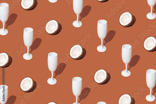 White champagne glasses with coconut. Minimal pattern and design. Brown background..