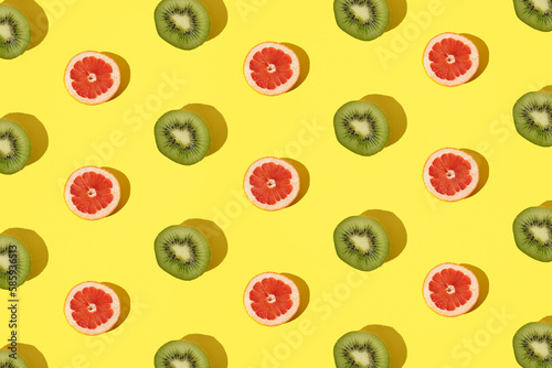 Fototapeta Naklejka Na Ścianę i Meble -  Arranged kiwi and grapefruit on a minimal yellow background.