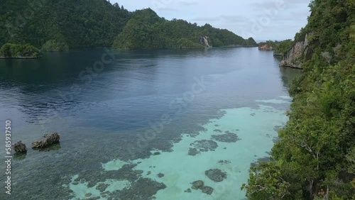 Aerial Footage. Flying close to a tropical island with lush plant growth and shallow reefs in clear water photo